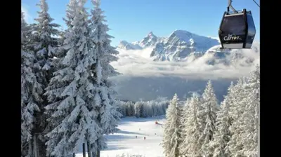 a ski lift flying over a snow covered mountain at Les Carroz d'Araches in Les Carroz d'Araches