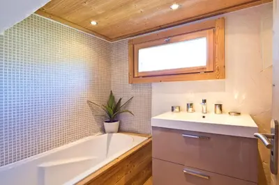 a bathroom with a bath tub and a sink at Chalet la Brunette in Megève