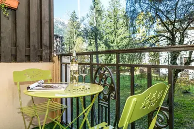 a table and two chairs on a balcony with a window at Apartment Chamois Blanc 1 - Central Chamonix Haven in Chamonix-Mont-Blanc