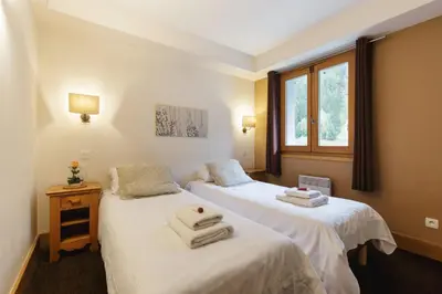 two beds in a room with towels on them at Vallorcine Mont Blanc Spa in Vallorcine