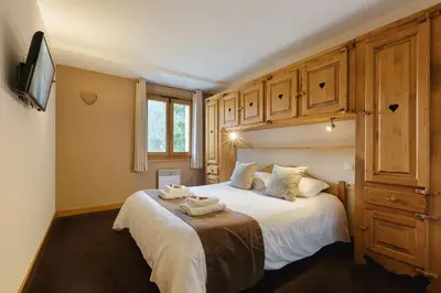 a bedroom with a large white bed with wooden cabinets at Vallorcine Mont Blanc Spa in Vallorcine