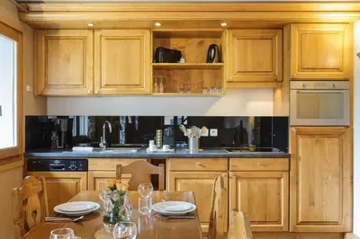 a kitchen with wooden cabinets and a wooden table at Vallorcine Mont Blanc Spa in Vallorcine