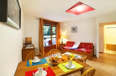 a living room with a table and a red couch at Résidence Goélia Le Nevez in Les Contamines-Montjoie