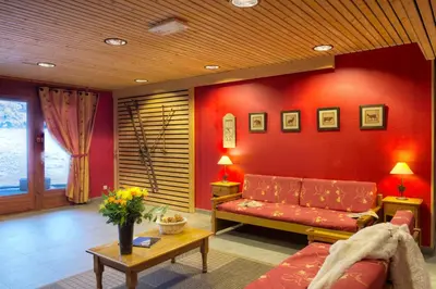 a living room with a couch and a red wall at Résidence Goélia Le Nevez in Les Contamines-Montjoie