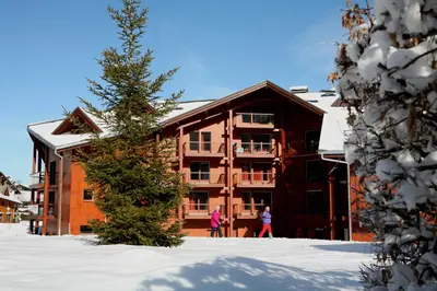 a building in the snow with two people in front at Résidence Goélia Le Nevez in Les Contamines-Montjoie