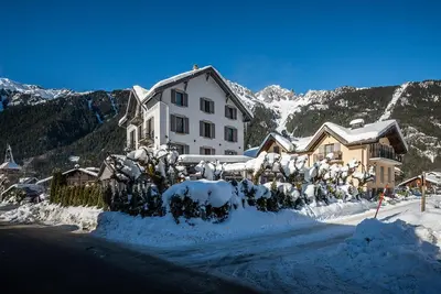 a large white house with snow on the ground at Eden Hotel, Apartments and Chalet Chamonix Les Praz in Chamonix-Mont-Blanc