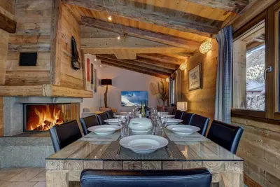 a dining room with a long table and a fireplace at Chalet Capricorne in Chamonix-Mont-Blanc