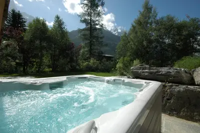 a hot tub in a garden with mountains in the background at Chalet Capricorne in Chamonix-Mont-Blanc
