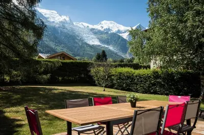 a wooden table and chairs with mountains in the background at Chalet Les Favrands in Chamonix-Mont-Blanc