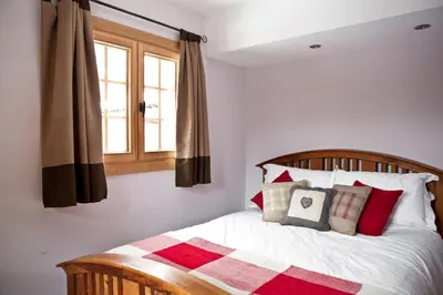 a bed with red and white pillows and a window at Chalet Les Favrands in Chamonix-Mont-Blanc