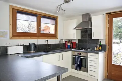 a kitchen with white cabinets and a black counter top at Chalet Les Favrands in Chamonix-Mont-Blanc