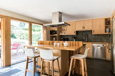 a kitchen with wooden cabinets and a island with bar stools at Chalet Les Favrands in Chamonix-Mont-Blanc