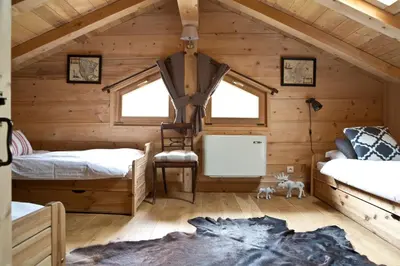 a log cabin bedroom with two beds and a chair at Chalet Amelie in Chamonix-Mont-Blanc