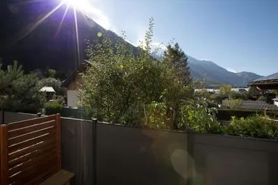 a fence with the sun shining on a mountain at Résidence Les Chamois in Chamonix-Mont-Blanc