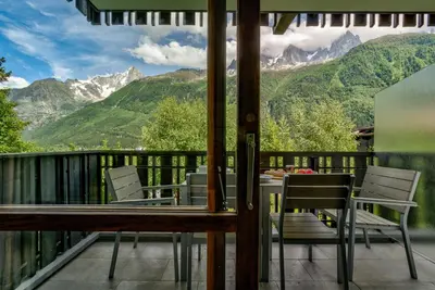 a balcony with a table and chairs and mountains at Le Brevent 3 Apartment in Chamonix-Mont-Blanc