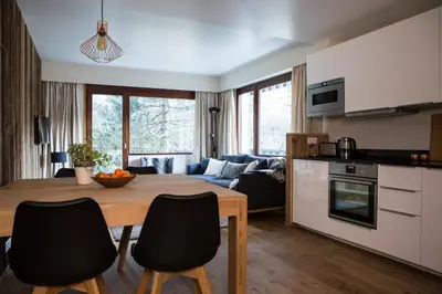 a kitchen and living room with a wooden table and chairs at Le Brevent 2 Apartment in Chamonix-Mont-Blanc