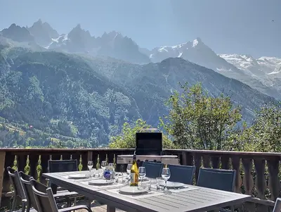 a table with wine glasses on a balcony with mountains at MontBlanc Balcony Chamonix in Chamonix-Mont-Blanc