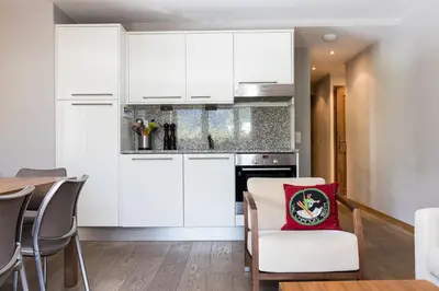 a kitchen with white cabinets and a table with a red pillow at Villa Floria Apartment in Chamonix-Mont-Blanc