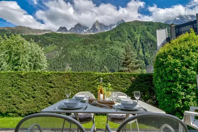 a table with glasses and food on it with mountains in the background at Villa Floria Apartment in Chamonix-Mont-Blanc