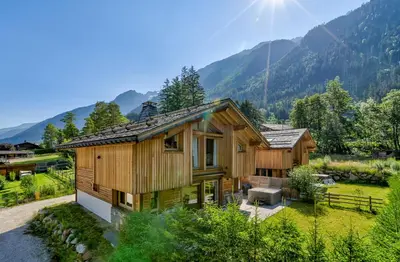 a wooden house with mountains in the background at Chalet Planards 1 in Chamonix-Mont-Blanc