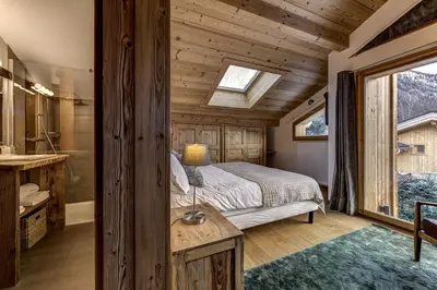 a bedroom with a bed and a bathroom with a tub at Chalet Planards 1 in Chamonix-Mont-Blanc