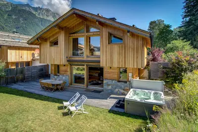 a wooden house with a deck and chairs in the yard at Chalet Planards 2 in Chamonix-Mont-Blanc