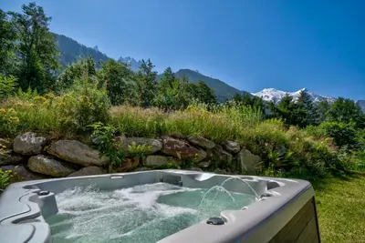 a bath tub with water in a field with mountains at Chalet Planards 2 in Chamonix-Mont-Blanc