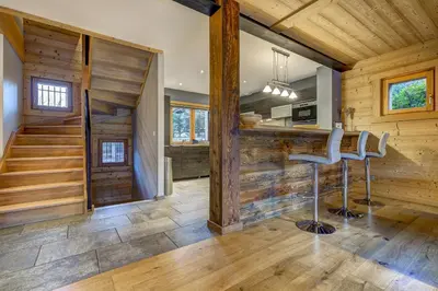 a kitchen and living room with wood walls and stools at Chalet Planards 2 in Chamonix-Mont-Blanc