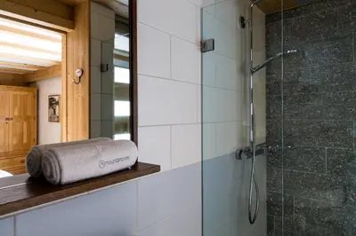 a bathroom with a shower and a towel on a shelf at Chalet Le Favre in Chamonix-Mont-Blanc