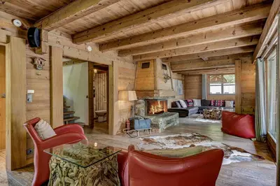 a living room with a fireplace and red chairs at Chalet les Sauberands in Chamonix-Mont-Blanc