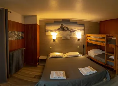 a room with two bunk beds and a bed with a book at Hotel La Chaumière à 180m du télécabine et de la gare in Saint-Gervais-les-Bains