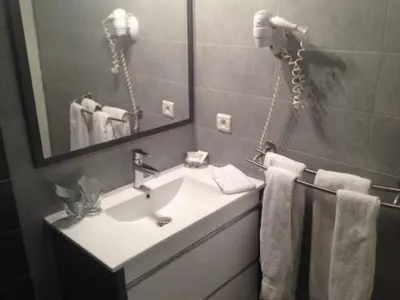a bathroom with a sink and a mirror and towels at Hotel La Chaumière à 180m du télécabine et de la gare in Saint-Gervais-les-Bains