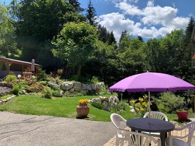 a purple umbrella sitting on a table in a garden at Le Moulin des Olirics in Sallanches