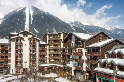 a hotel with snow covered mountains in the background at Cozy Chamonix Ski Studio with Mountain Views in Chamonix-Mont-Blanc