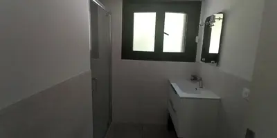 a white bathroom with a sink and a window at Gîte Montvauthier in Les Houches