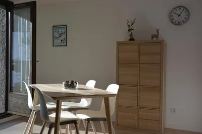 a dining room table with white chairs and a clock at Gîte Montvauthier in Les Houches