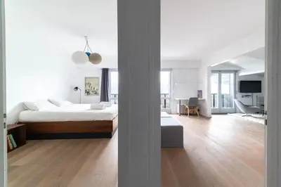 a white bedroom with a bed and a living room at Residence du Brevent in Chamonix-Mont-Blanc