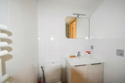 a white bathroom with a toilet and a mirror at Résidence Grand Roc - Campanules 308 - Happy Rentals in Chamonix-Mont-Blanc