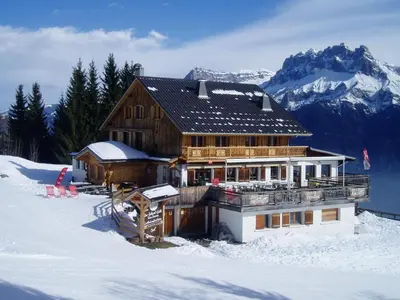 a large wooden house in the snow with mountains at Le Refuge in Cordon