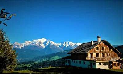 a house on a hill with mountains in the background at Le Refuge in Cordon