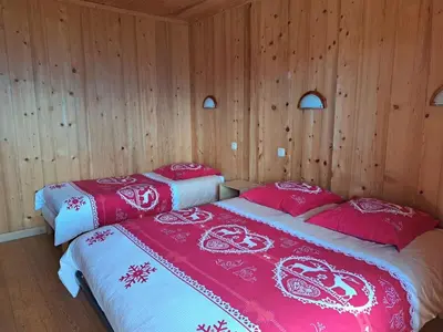 two beds in a room with wooden walls at Le Refuge in Cordon