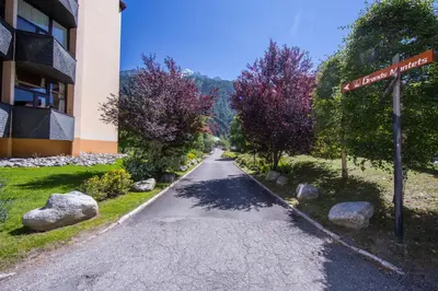 a church with a tree in front of a mountain at Résidence Grand Roc - Campanules 303 - Happy Rentals in Chamonix-Mont-Blanc