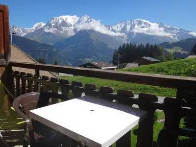 a white table and chairs on a balcony with mountains at Chalet Gabriel in Saint-Gervais-les-Bains