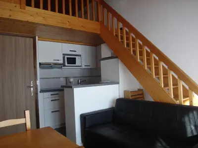 a living room with a couch and a kitchen with a staircase at Chalet Gabriel in Saint-Gervais-les-Bains