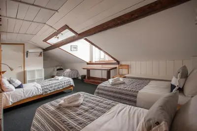 a attic room with three beds and a window at La Chaumière Mountain Lodge in Chamonix-Mont-Blanc
