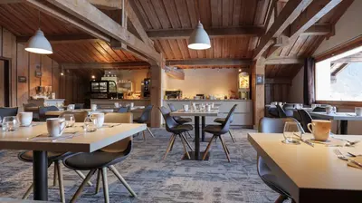 a restaurant with wooden ceilings and tables and chairs at Hôtel Le Labrador in Chamonix-Mont-Blanc