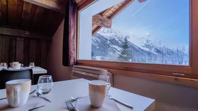 a dining room with a table and a large window at Hôtel Le Labrador in Chamonix-Mont-Blanc