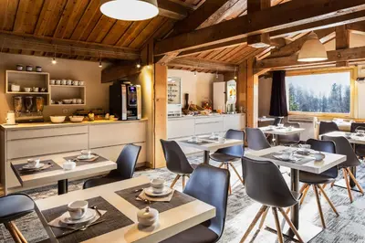 a restaurant with tables and chairs and a kitchen at Hôtel Le Labrador in Chamonix-Mont-Blanc