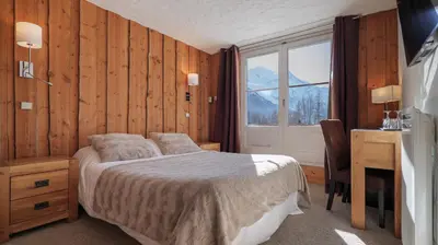 a bedroom with a bed and a desk and a window at Hôtel Le Labrador in Chamonix-Mont-Blanc