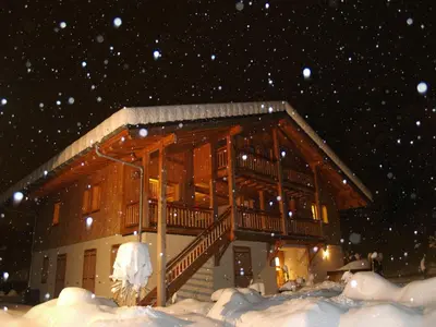 a house in the snow with snow falling at Chalet Brio in Samoëns